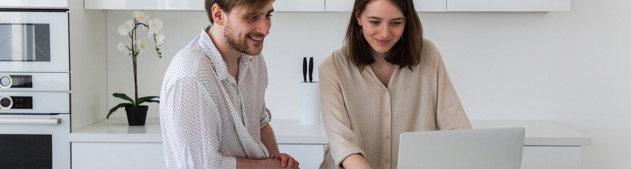 Two people reviewing financing details on a laptop in their kitchen.