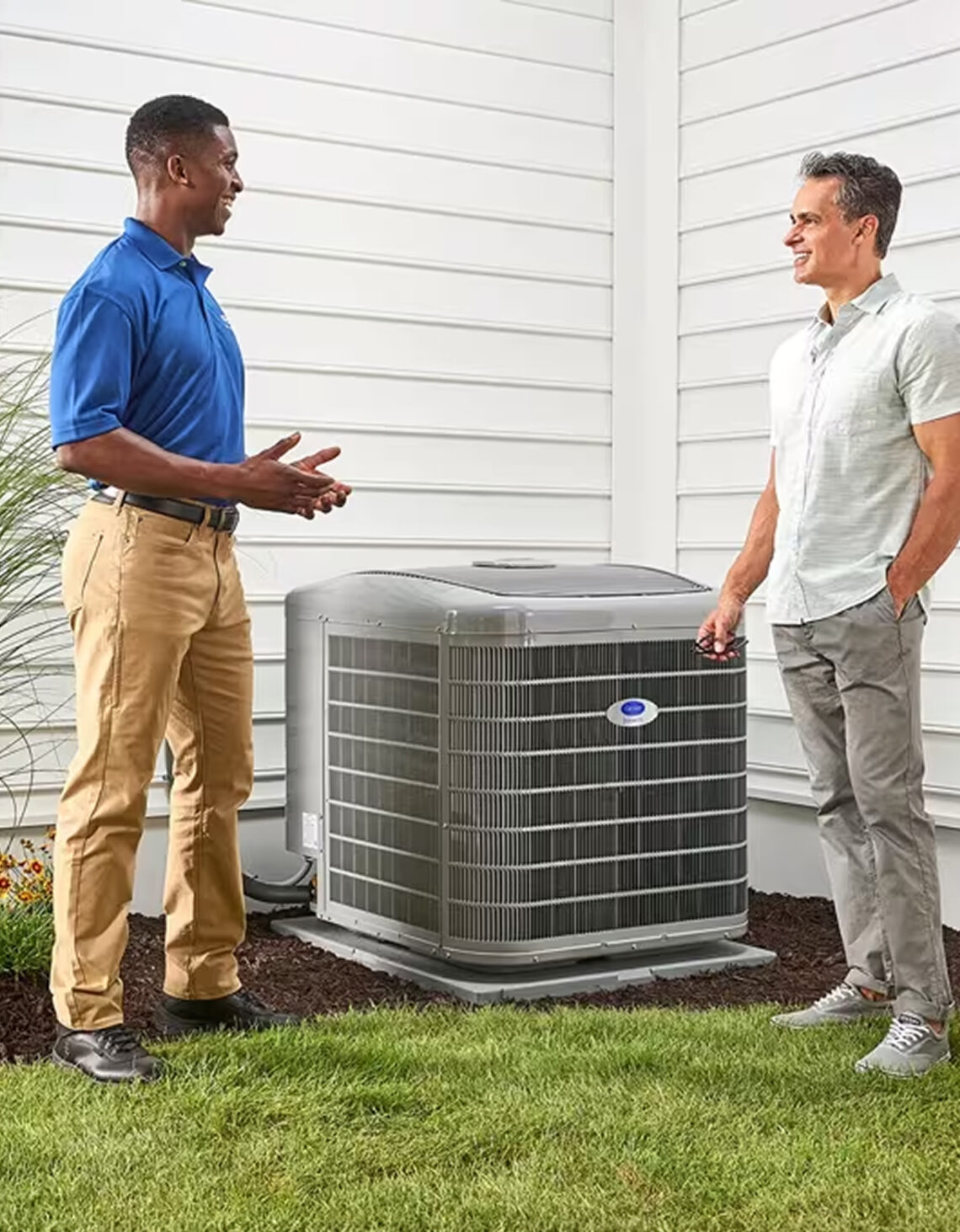 Comfort Solutions HVAC tech talking to a client outside the house next to the heat pump unit.