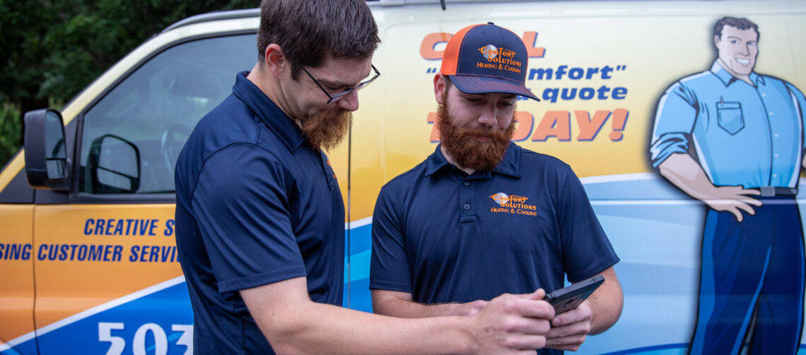 Two Comfort Solutions HVAC technicians reviewing project details outside their van.
