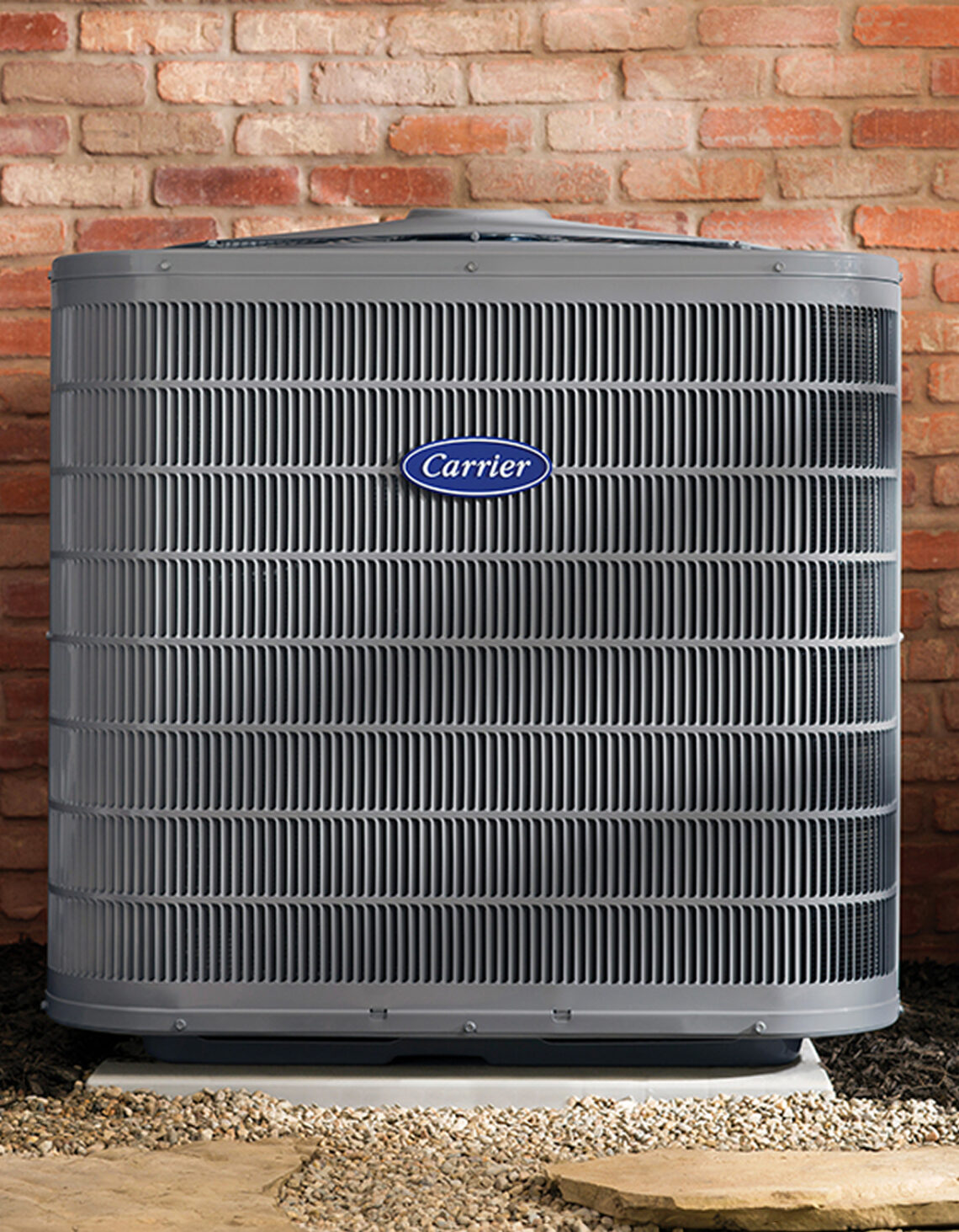 Heat pump outside a building shown in front of a red brick wall.