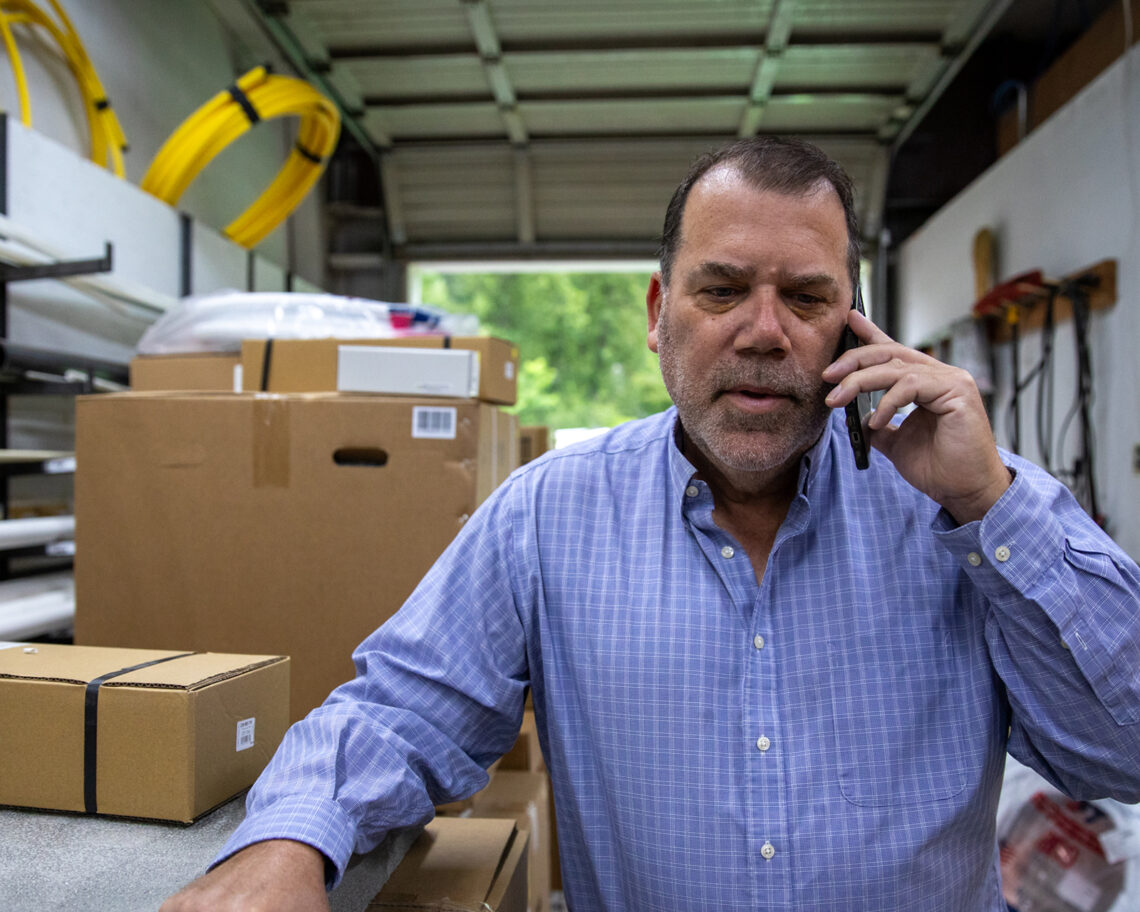 Comfort Solutions team member taking a call among stocked HVAC parts and supplies