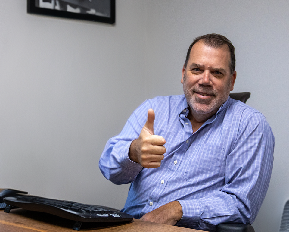 Comfort Solutions team member giving a thumbs up at his desk