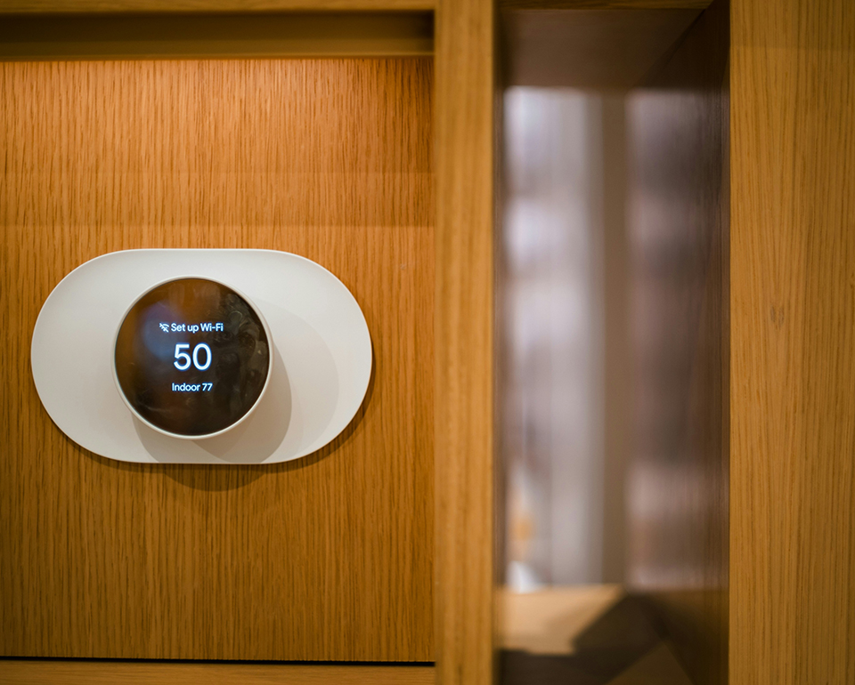 Smart thermostat mounted on a wood-panelled wall showing the indoor temperature